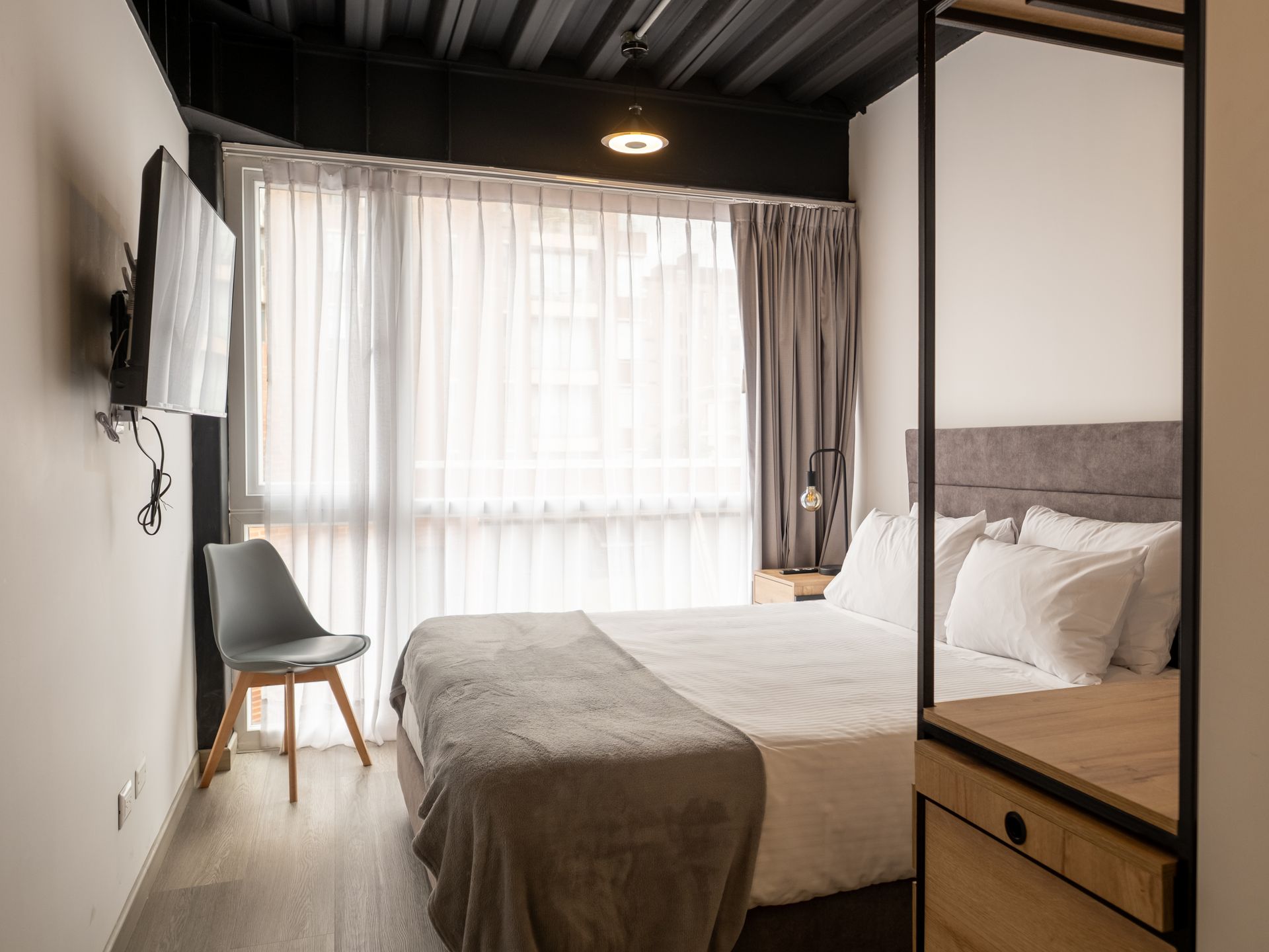 Habitación de apartasuites en Bogotá, con cama doble, clóset abierto y escritorio en Nova Iorque.