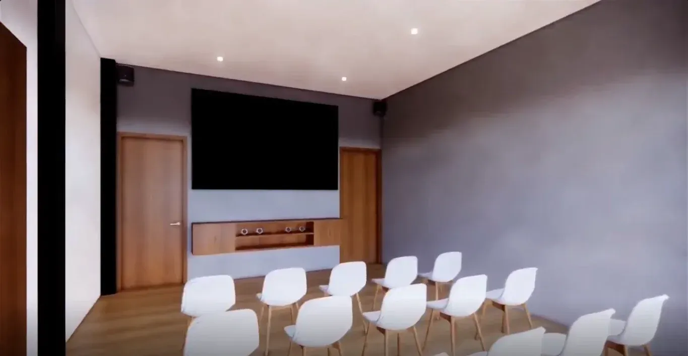 Hotel con auditorio para reuniones y eventos en Bogotá, con sillas blancas, pantalla y espacio interior moderno.