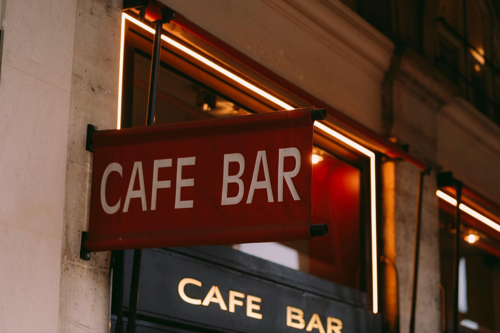 Red cafe bar sign glowing outside a storefront at night