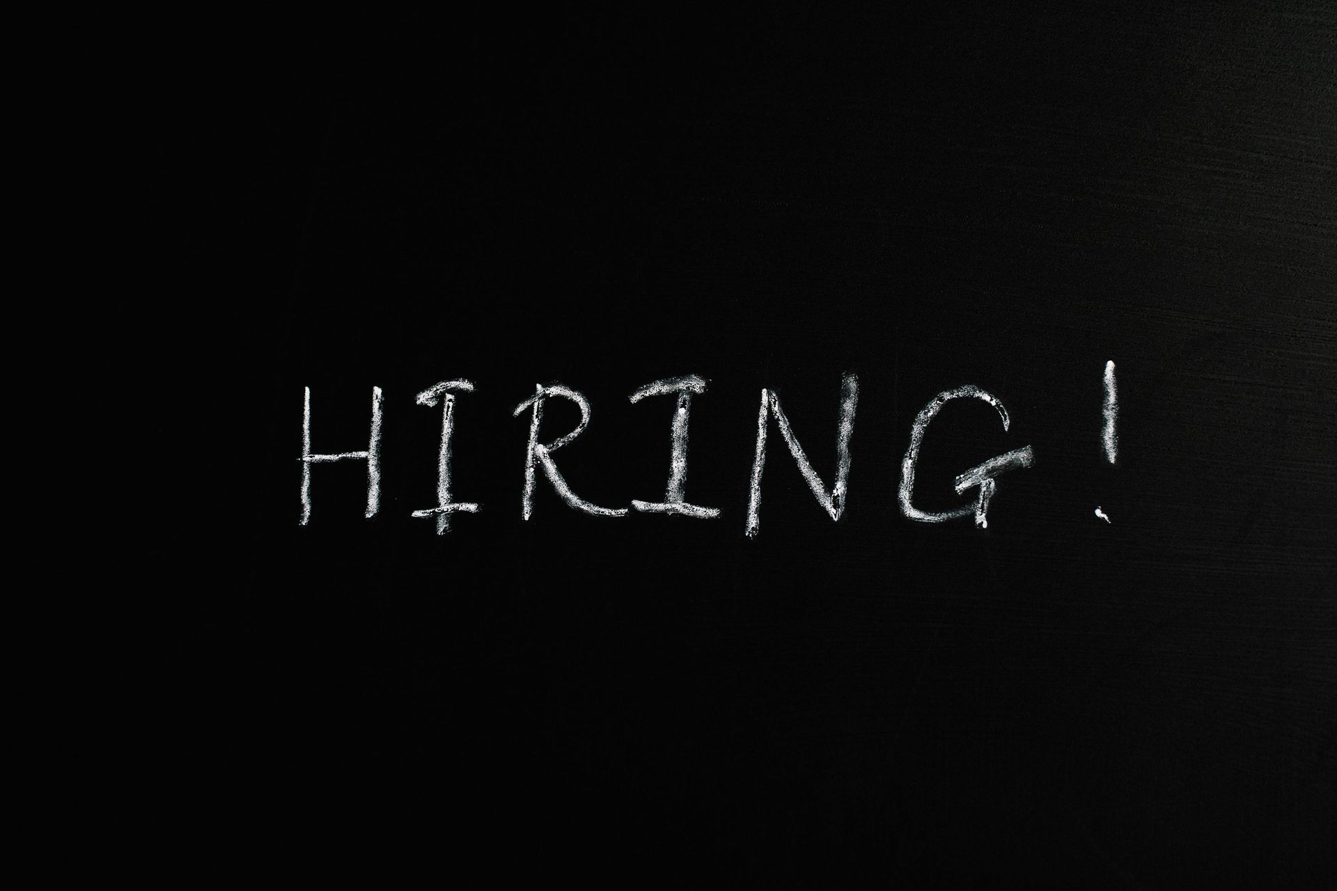 Chalk-style word “HIRING!” in white on a dark background
