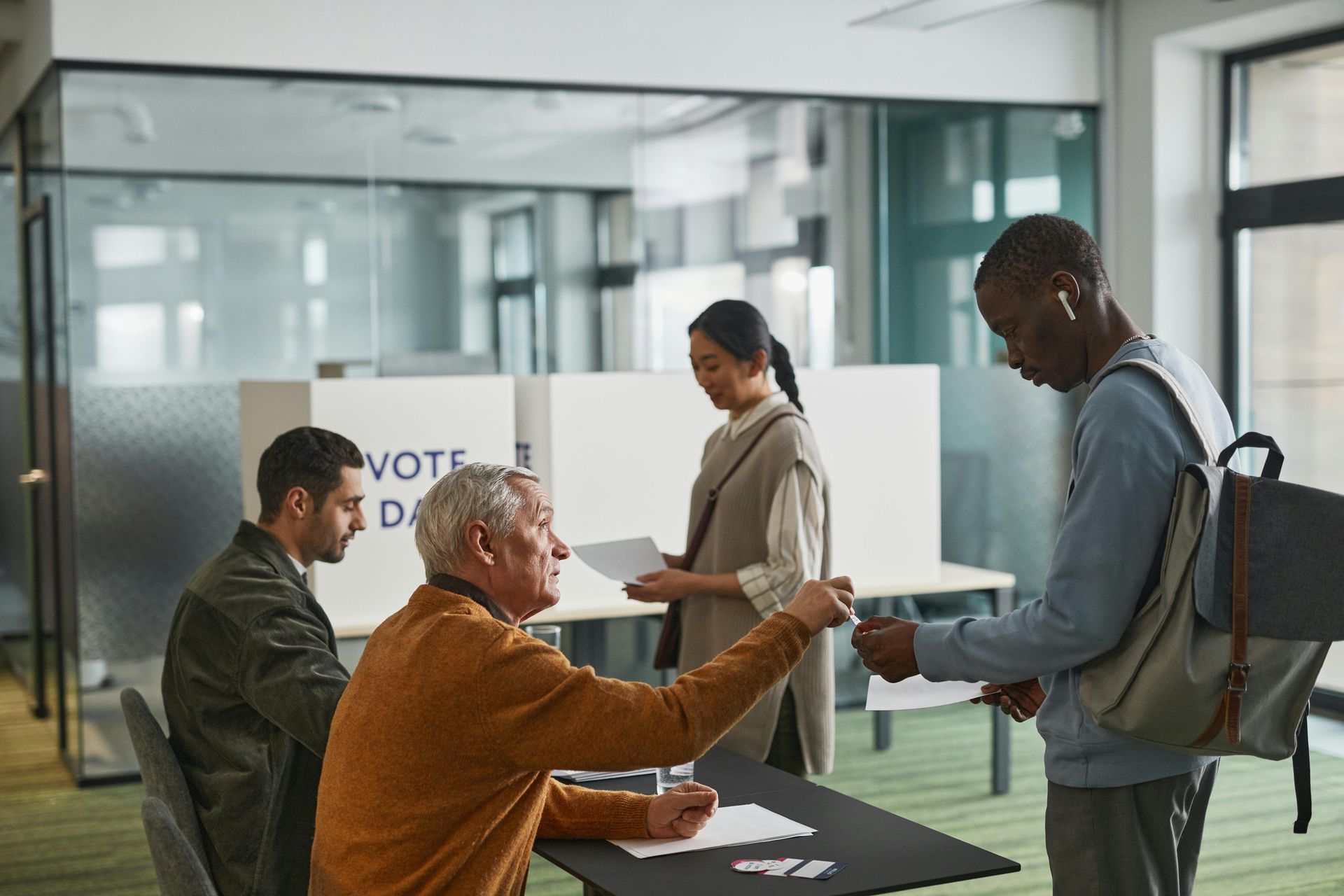 People signing in at a polling station with election staff at a registration table