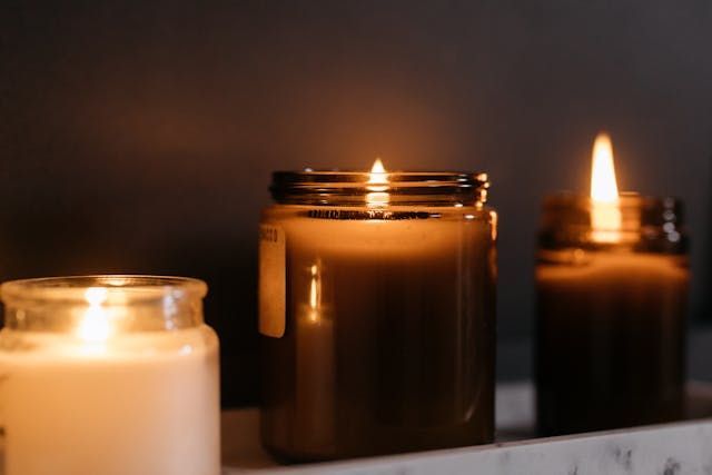Three softly glowing candles in glass jars create a comforting scene for Roanoke, VA cremations
