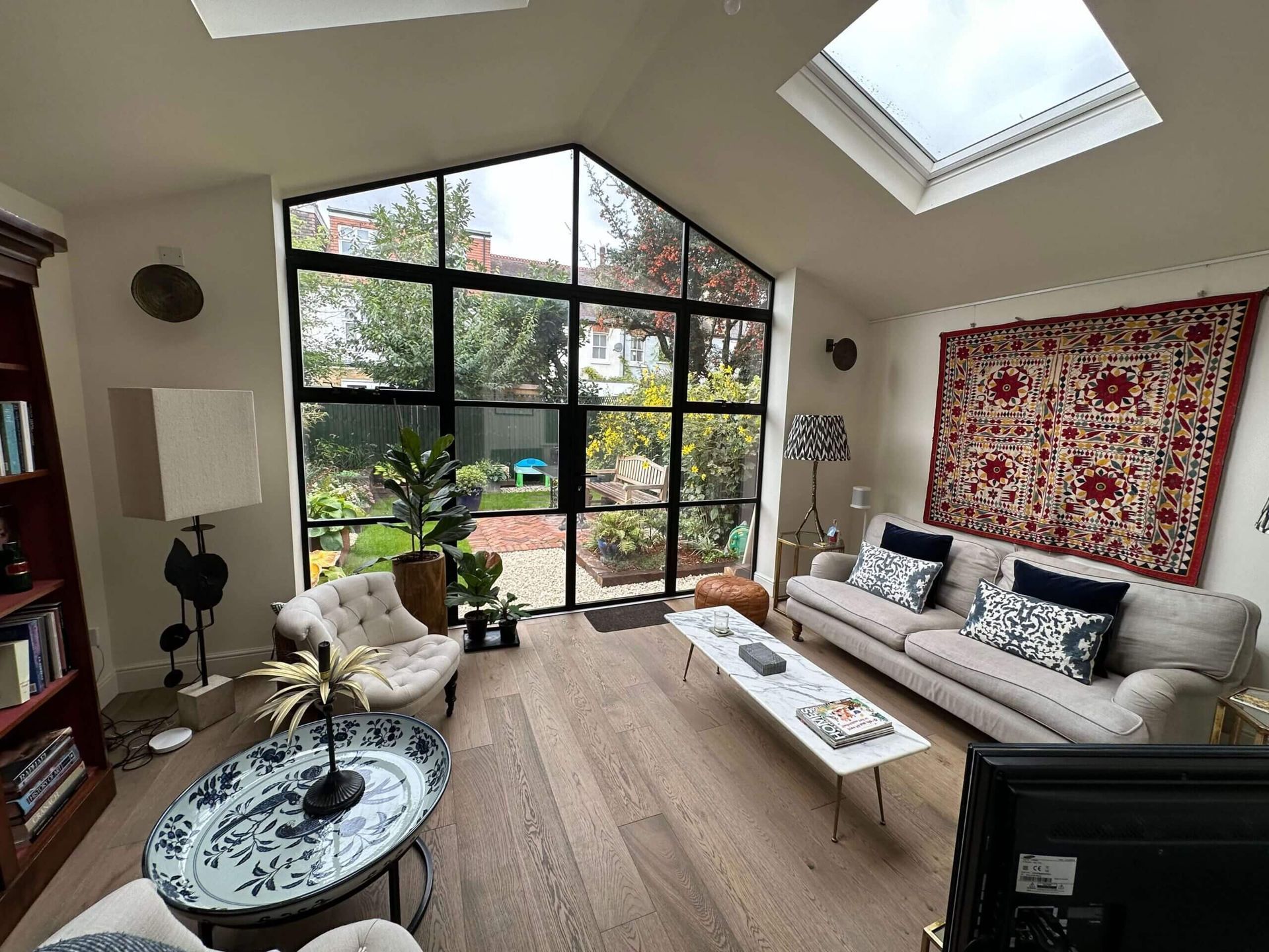 A living room with a couch , table , chairs and a skylight.