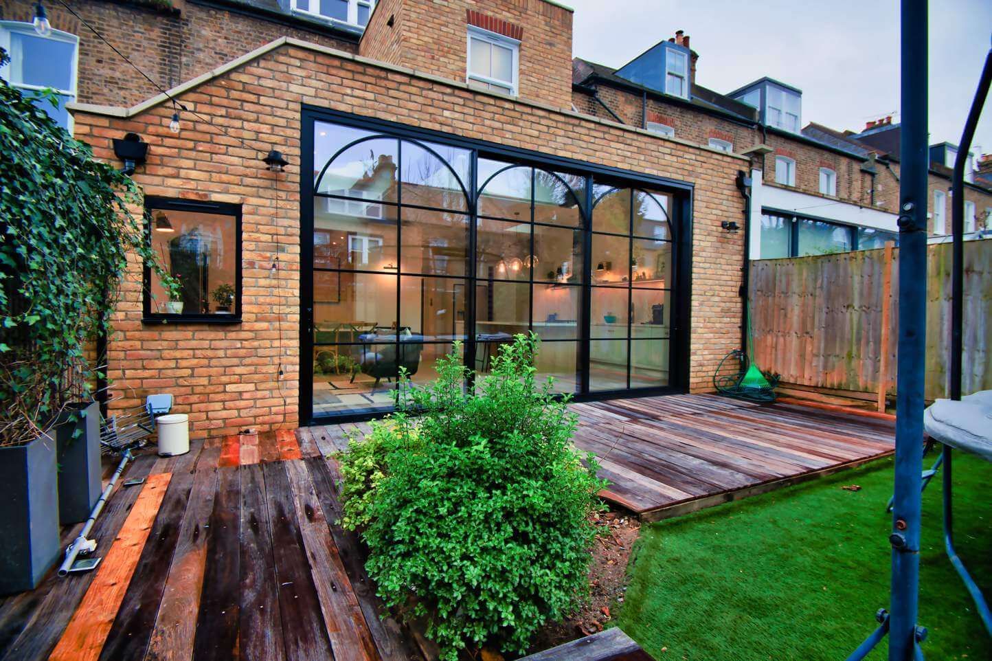 A brick house with a large window and a wooden deck in front of it.