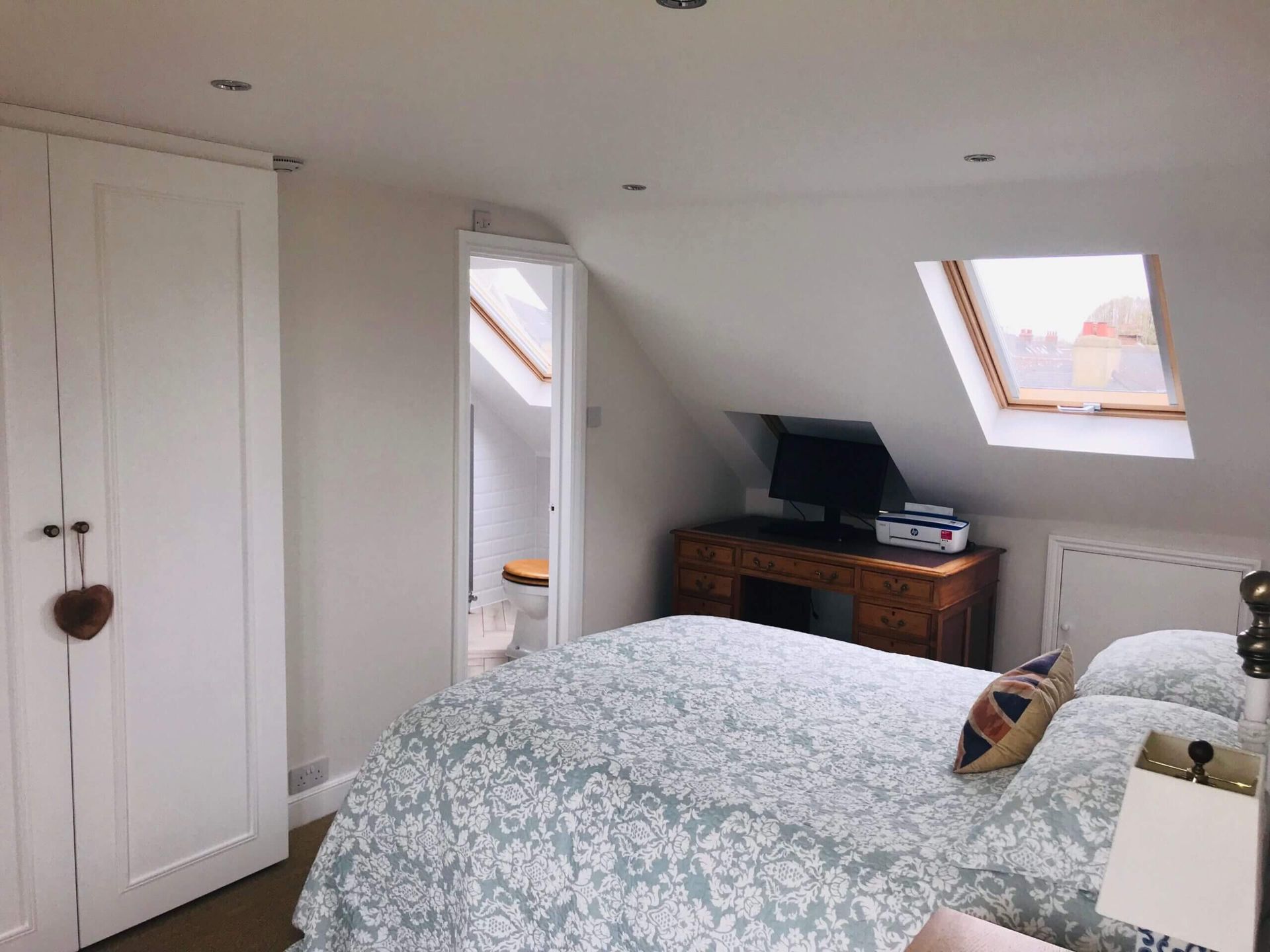 A bedroom with a bed and a skylight in the ceiling.