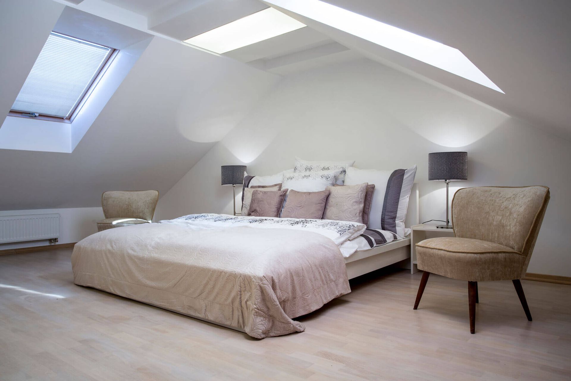 A bedroom with a bed , chairs , lamps and a skylight.