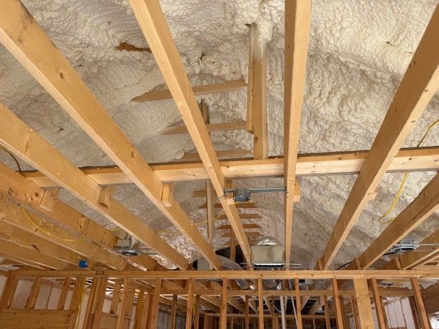 Interior view of a building's exposed wooden frame, insulation, and electrical components.
