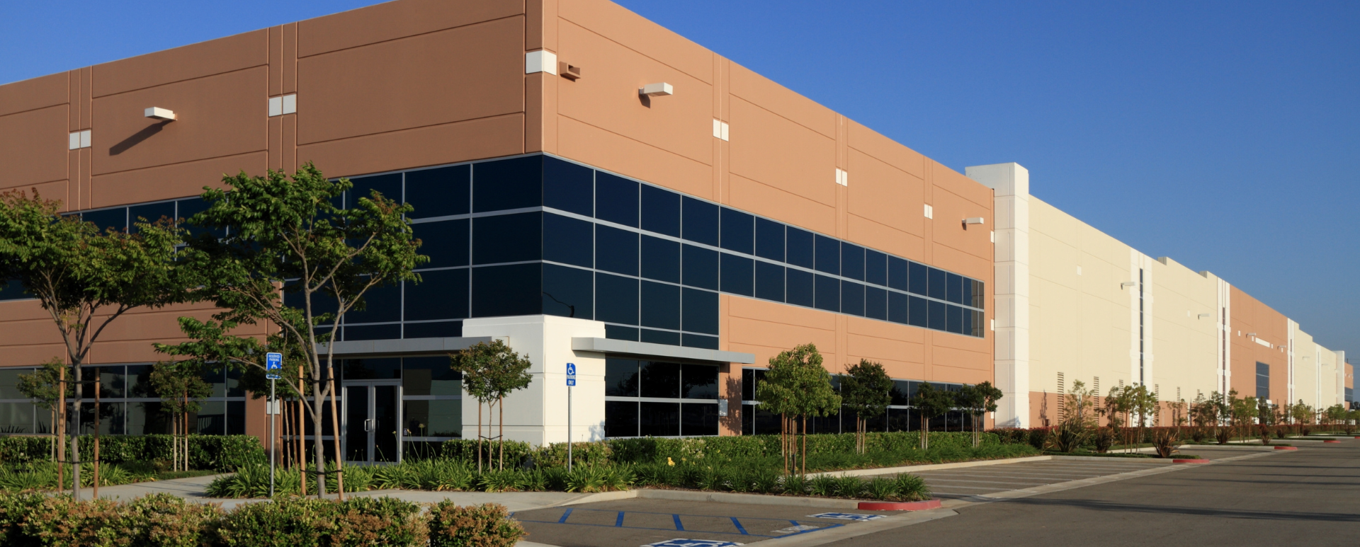 A man in a protective suit is spraying chemicals in a warehouse.