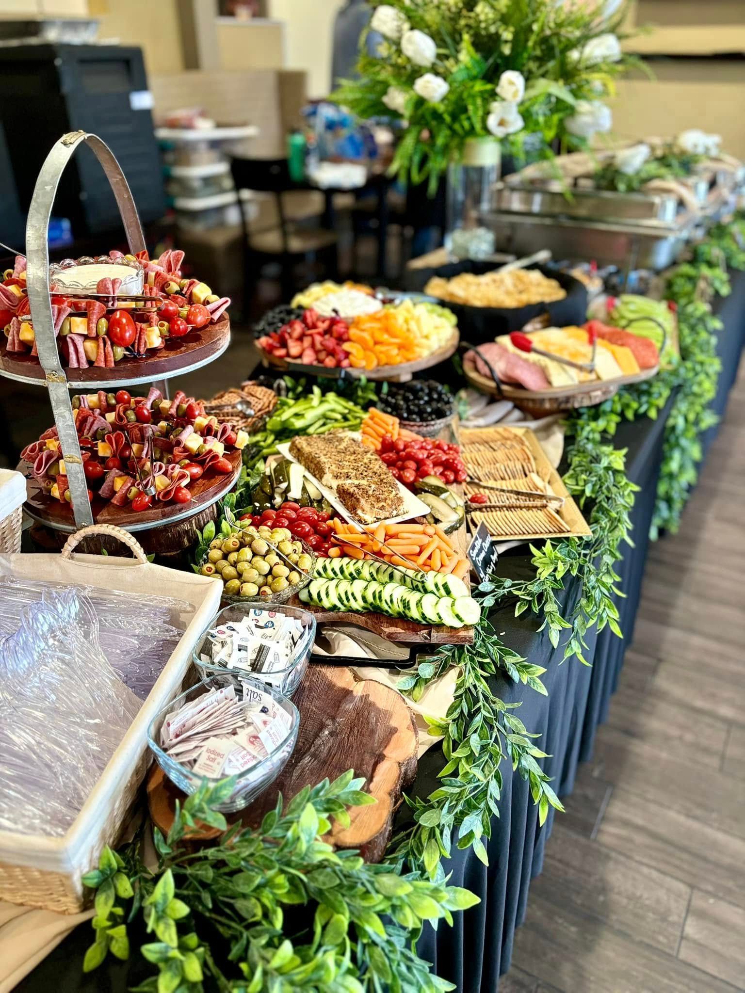 A long buffet table filled with lots of finger foods - meat, cheese, and vegetables.