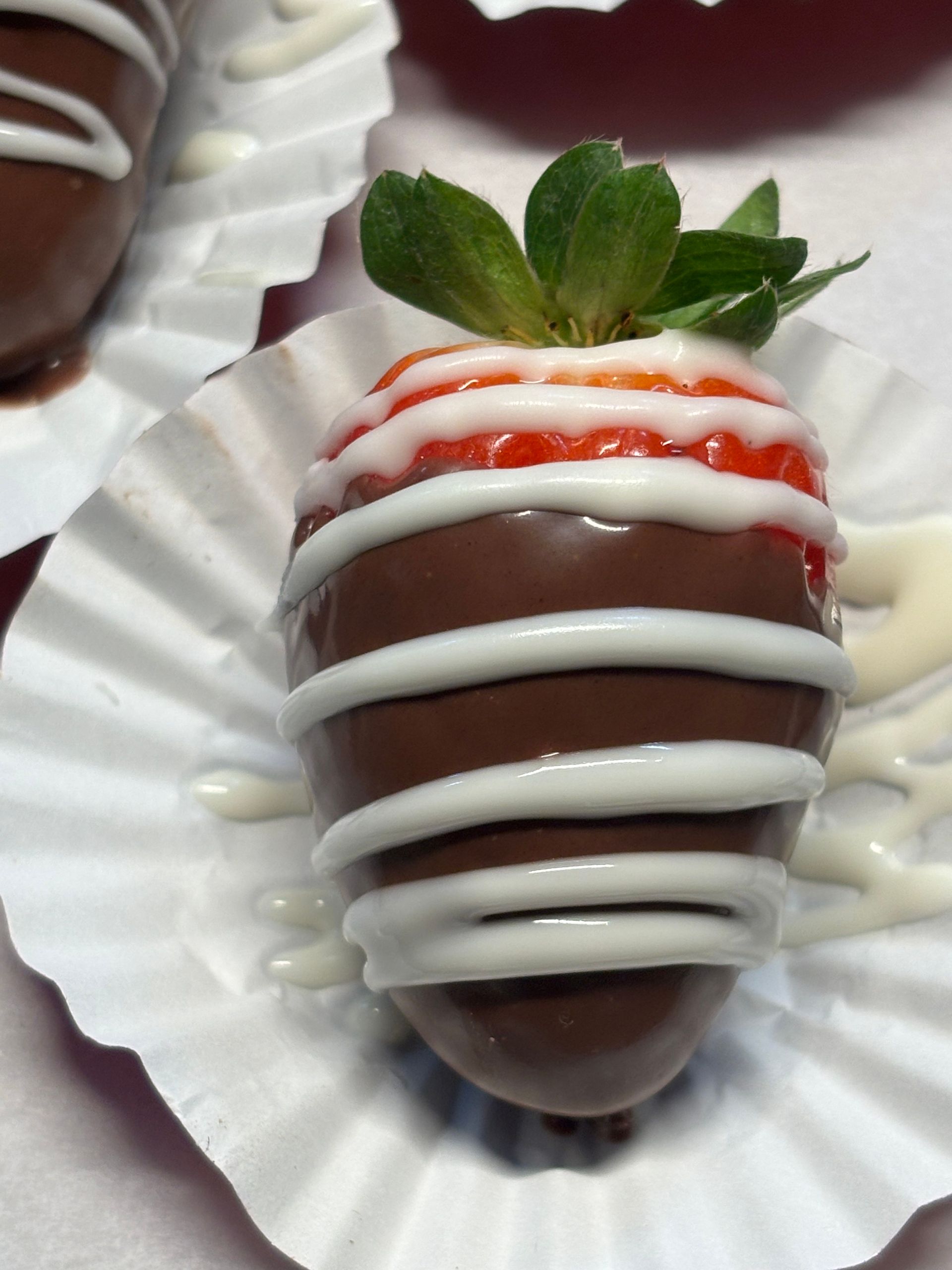 A chocolate covered strawberry with white icing on it