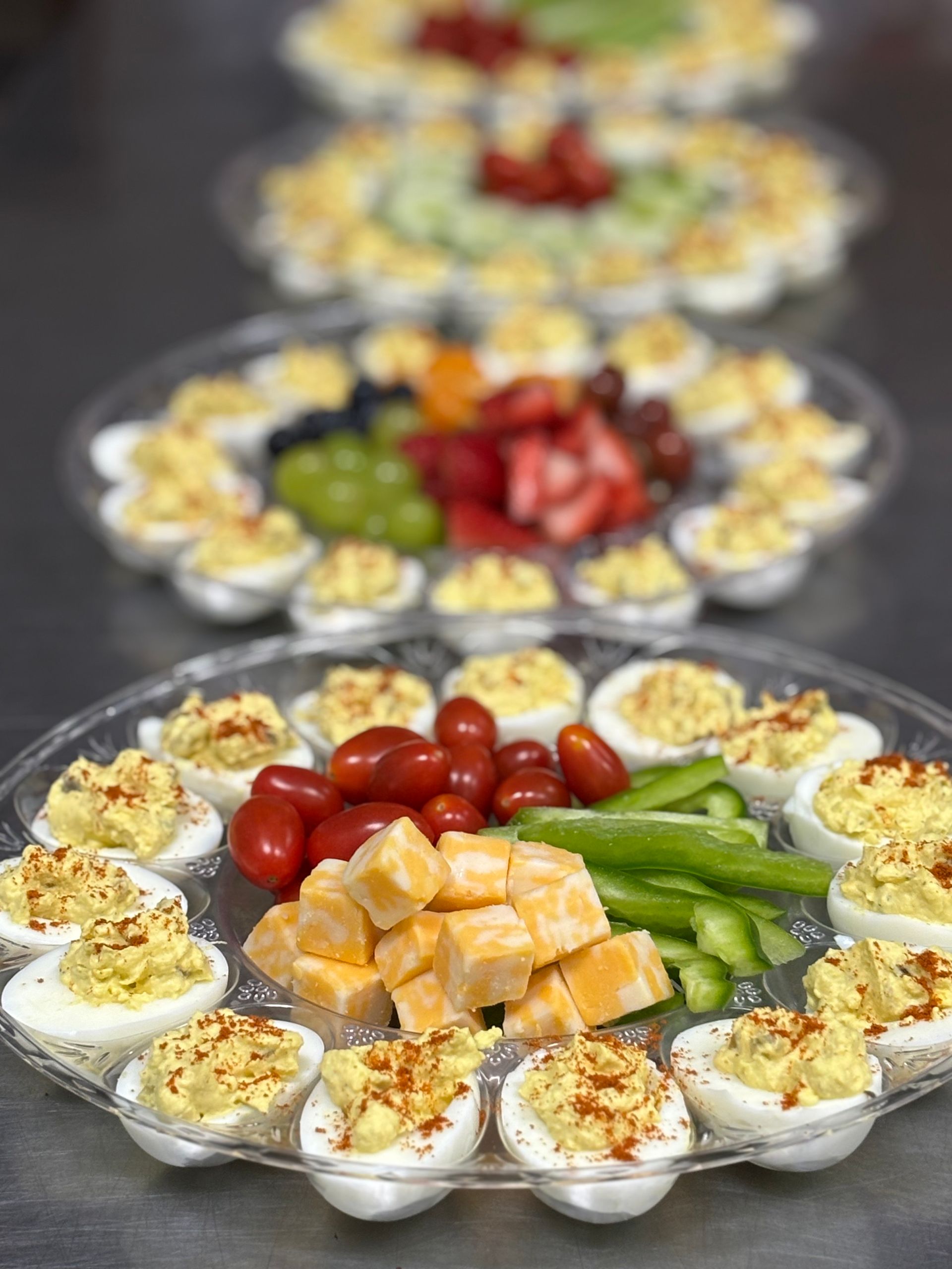 A plate of deviled eggs, cheese , tomatoes , and asparagus on a table.