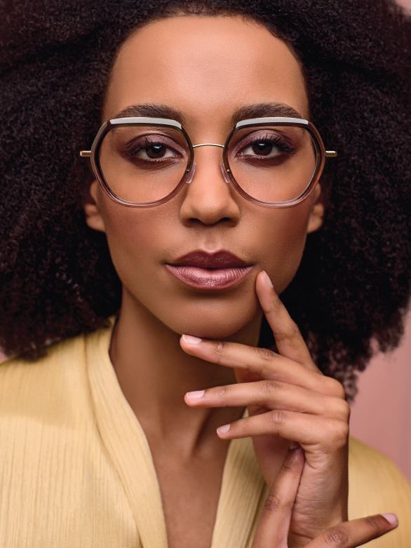 A woman wearing glasses is touching her face with her hand