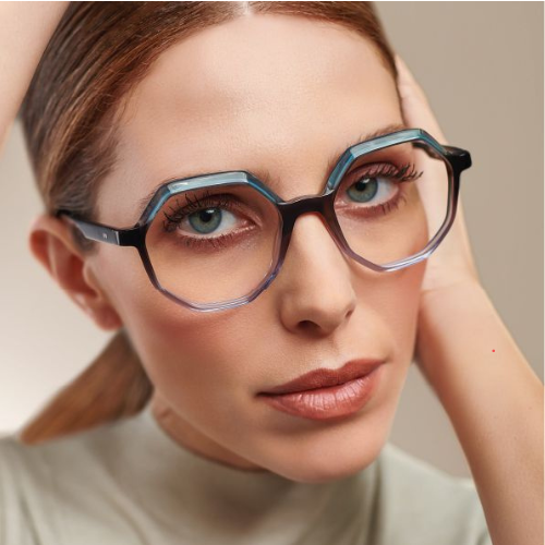 A woman wearing acetate glasses is holding her hand to her face.