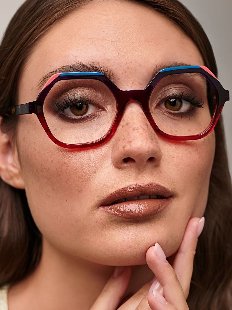 A close up of a woman wearing glasses and touching her face.