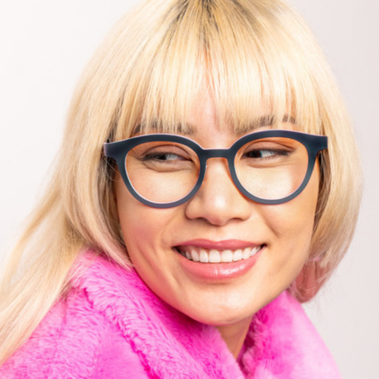 A woman wearing glasses and a pink coat is smiling