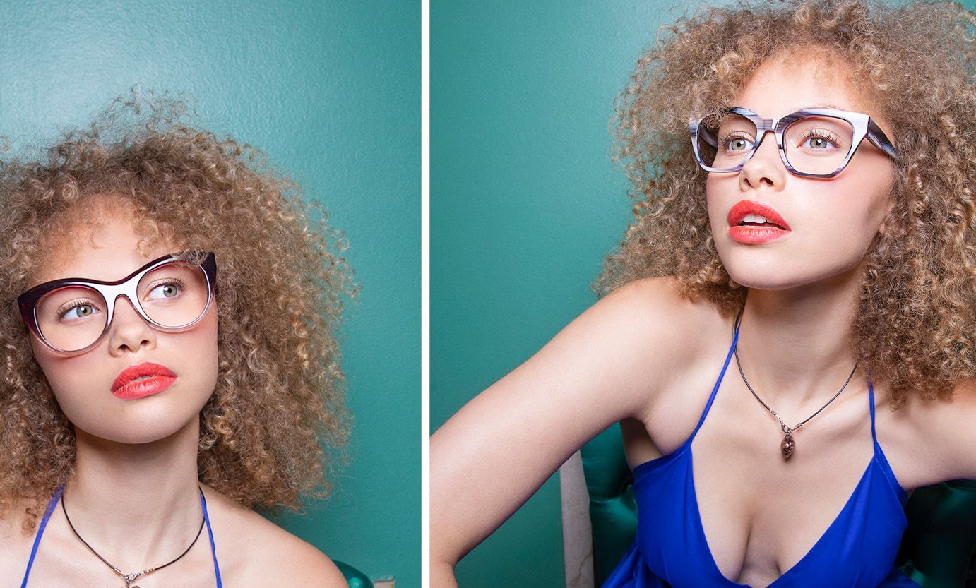 A woman with curly hair wearing glasses and a blue dress