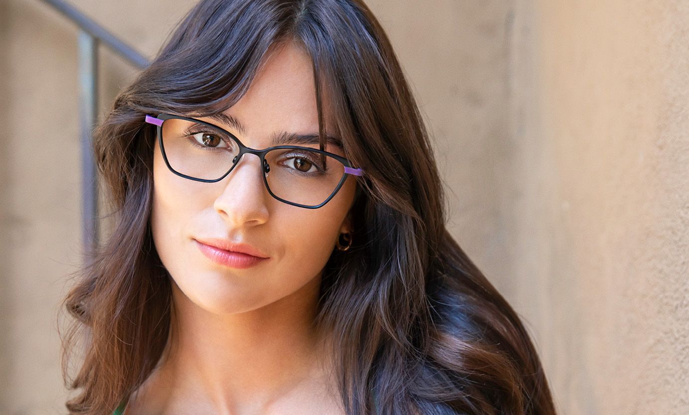 A woman wearing glasses is looking at the camera.