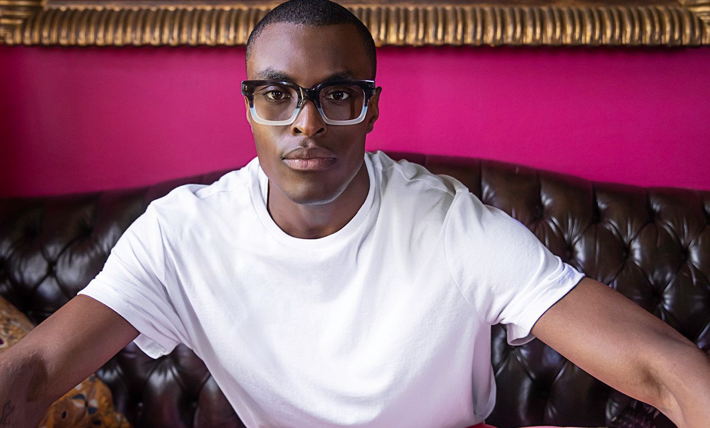 A man wearing glasses and a white shirt is sitting on a couch.