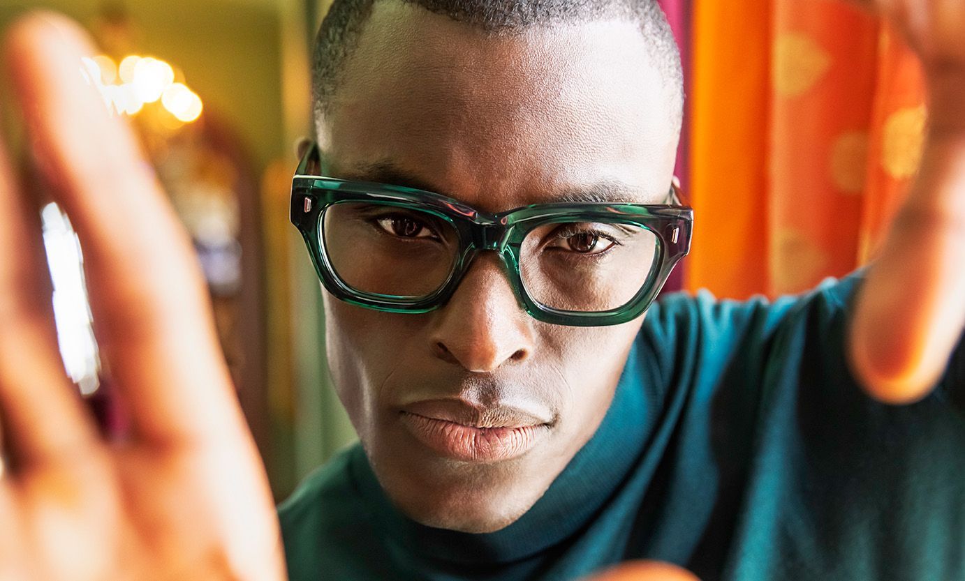 A close up of a man wearing glasses and a green turtleneck.