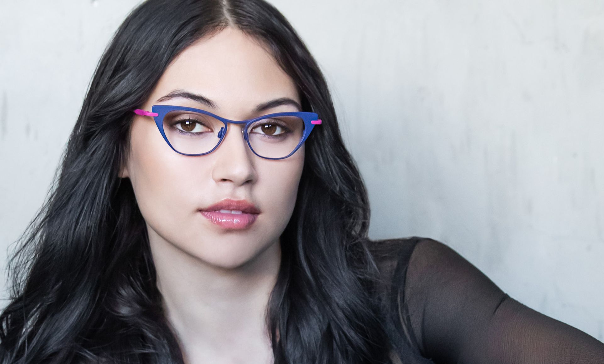 A woman wearing glasses and a black shirt is looking at the camera.