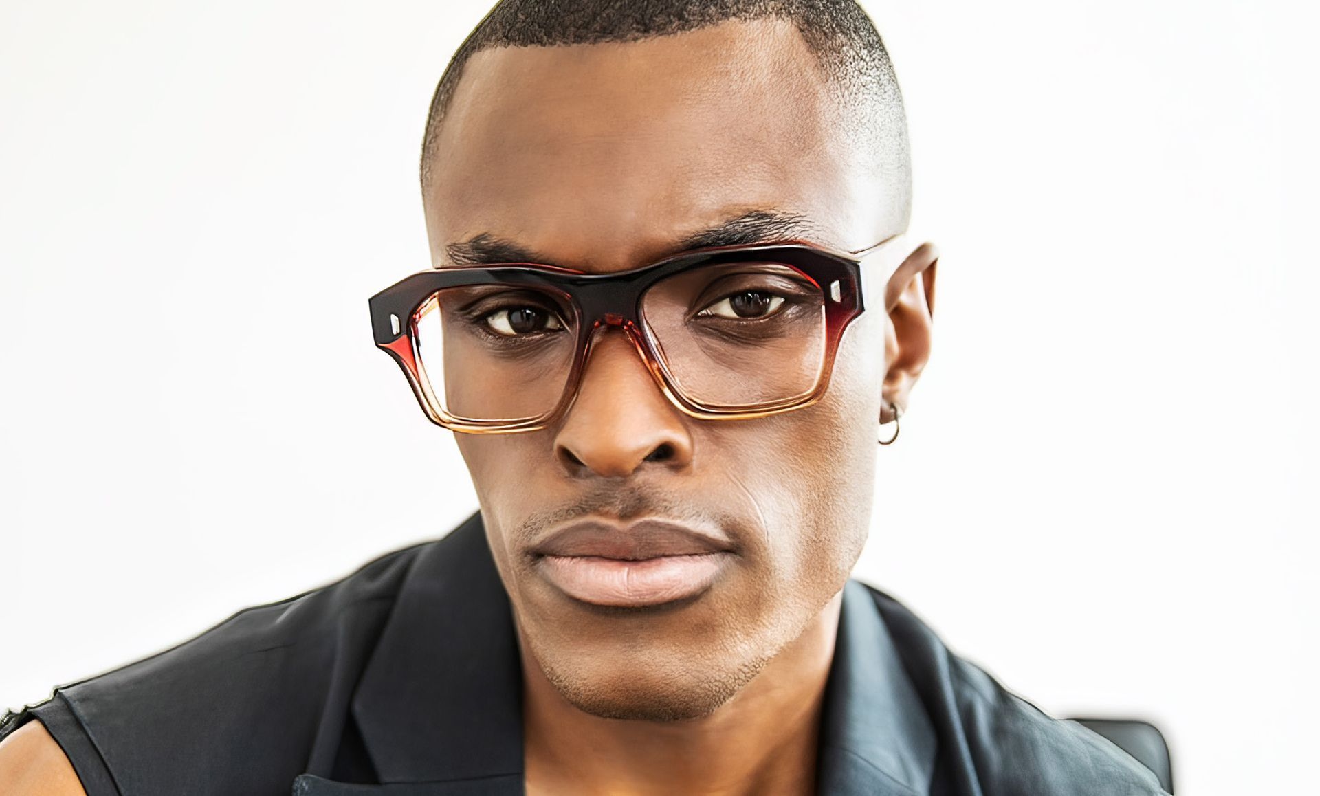 A man wearing glasses and a black shirt is looking at the camera.