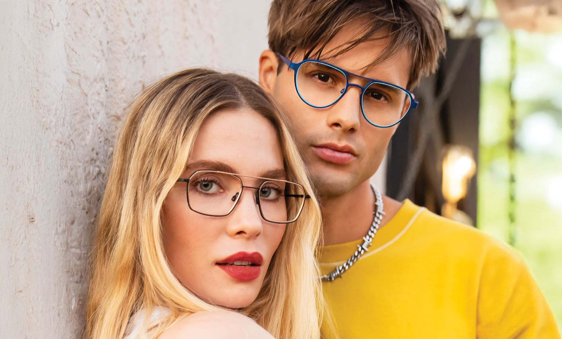 A man and a woman wearing glasses are standing next to each other.