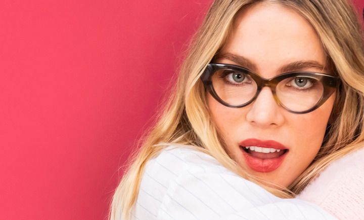 The woman is wearing glasses and a white sweater.