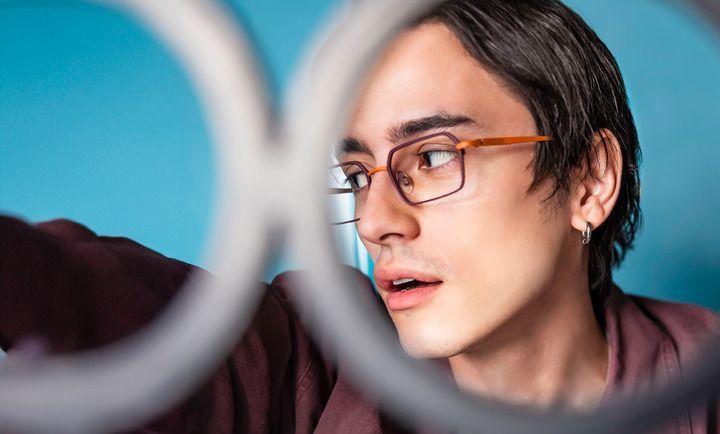 A man wearing glasses is looking through a ring.