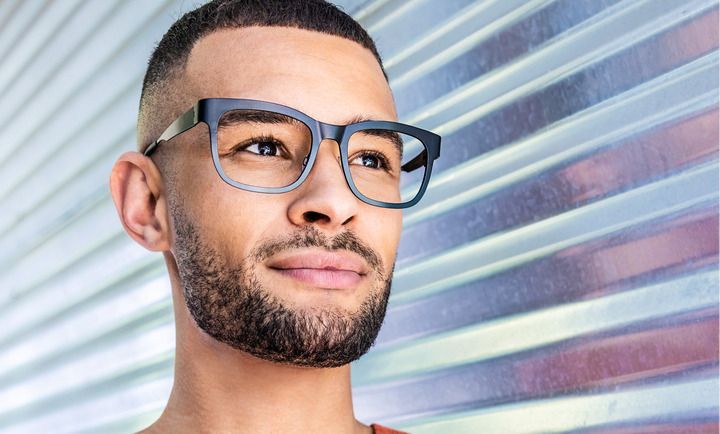 A man with a beard and glasses is smiling and looking up.