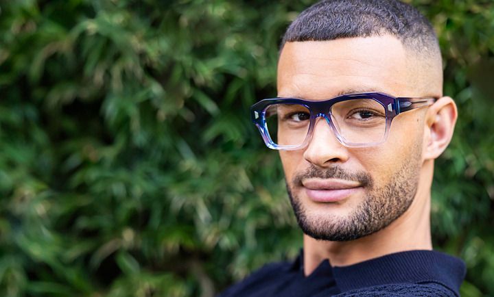 A close up of a man wearing glasses and a black shirt.