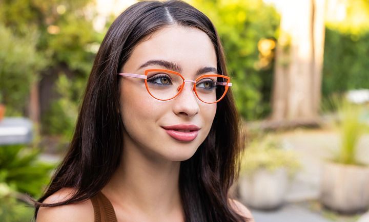 A woman wearing glasses is standing in a park.