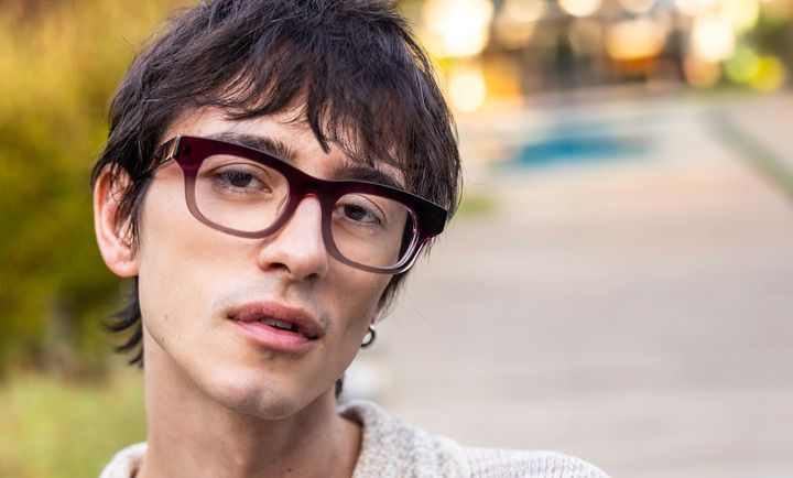 A young man wearing glasses is looking at the camera.