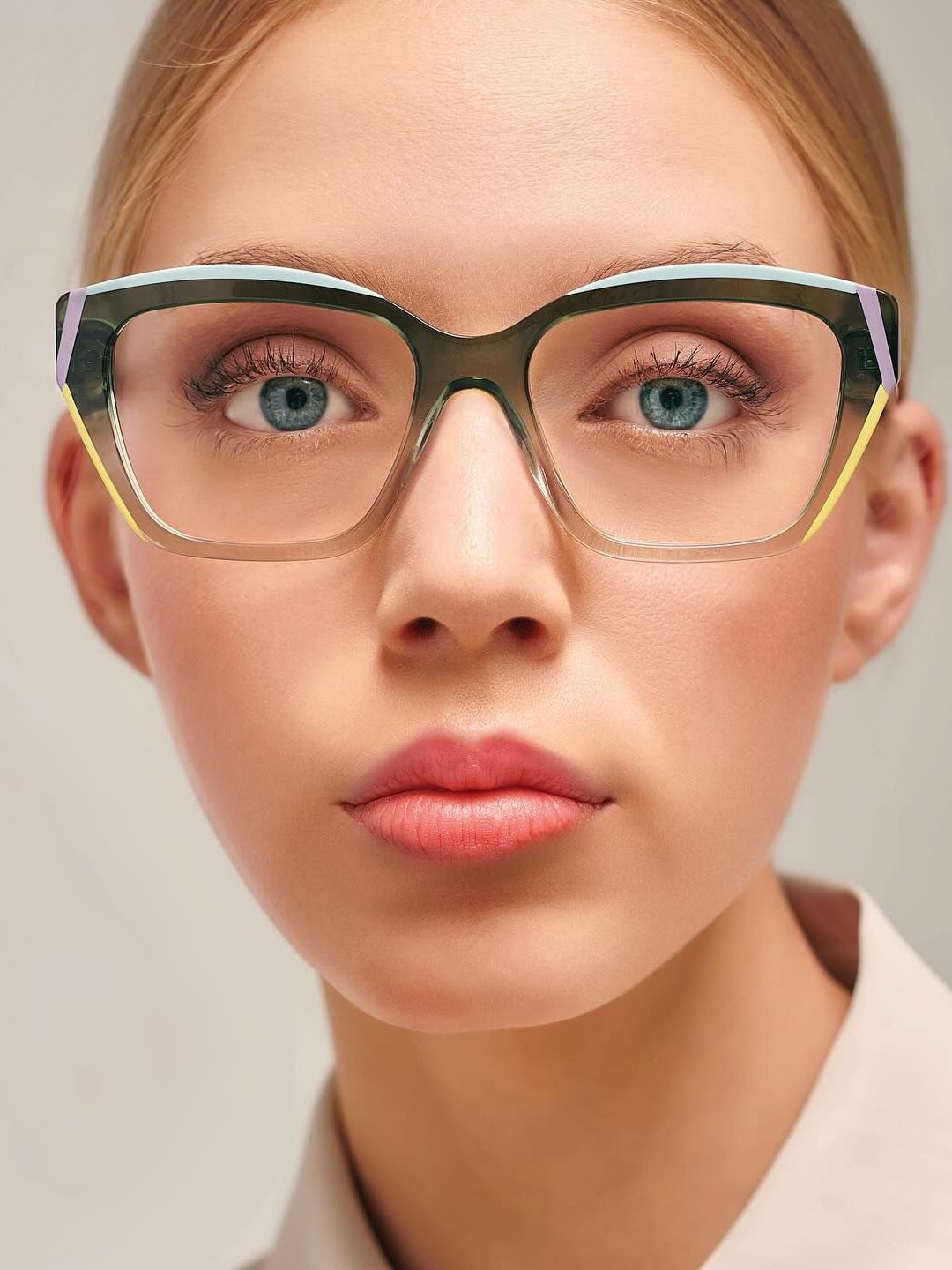 A close up of a woman wearing glasses and a white shirt