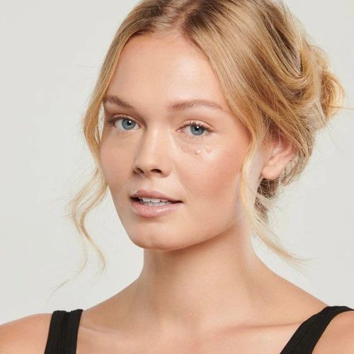 A woman with blonde hair is wearing a black tank top while using Total Eye® SPF 35.