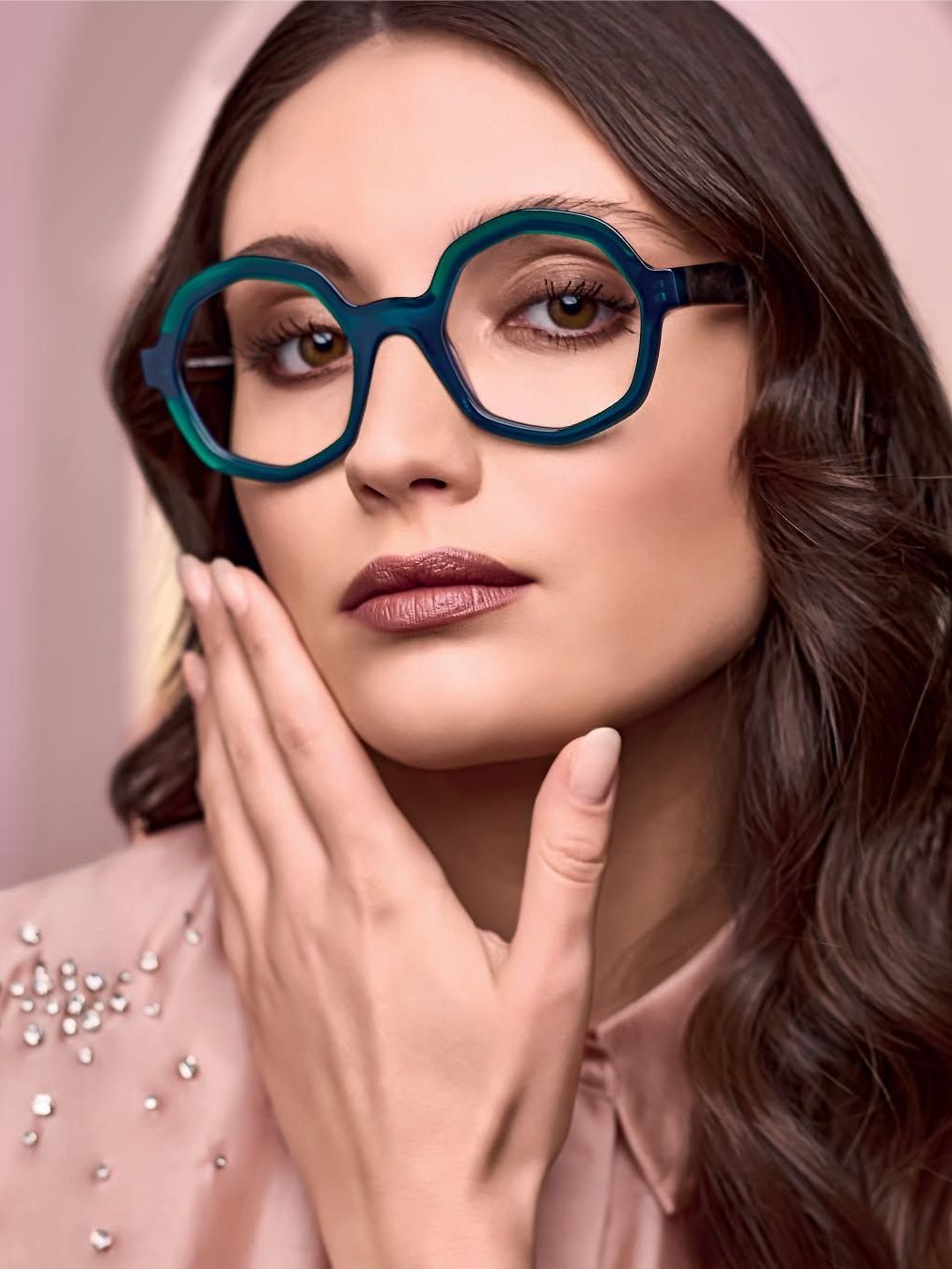 A woman wearing glasses is touching her face with her hand.