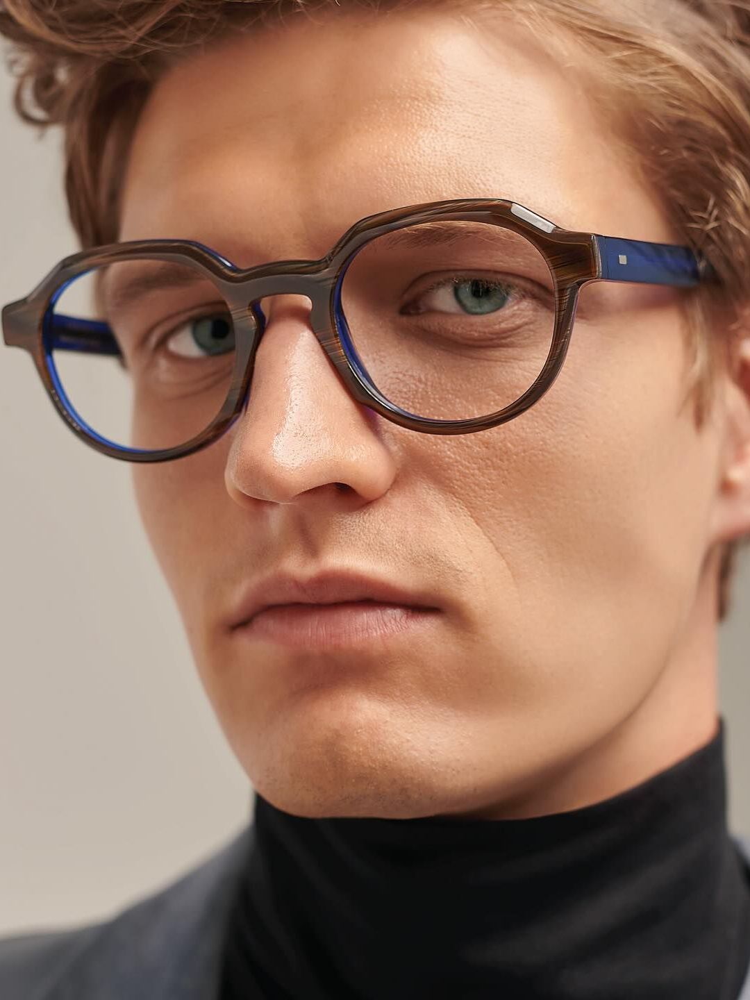 A close up of a man wearing glasses and a black turtleneck