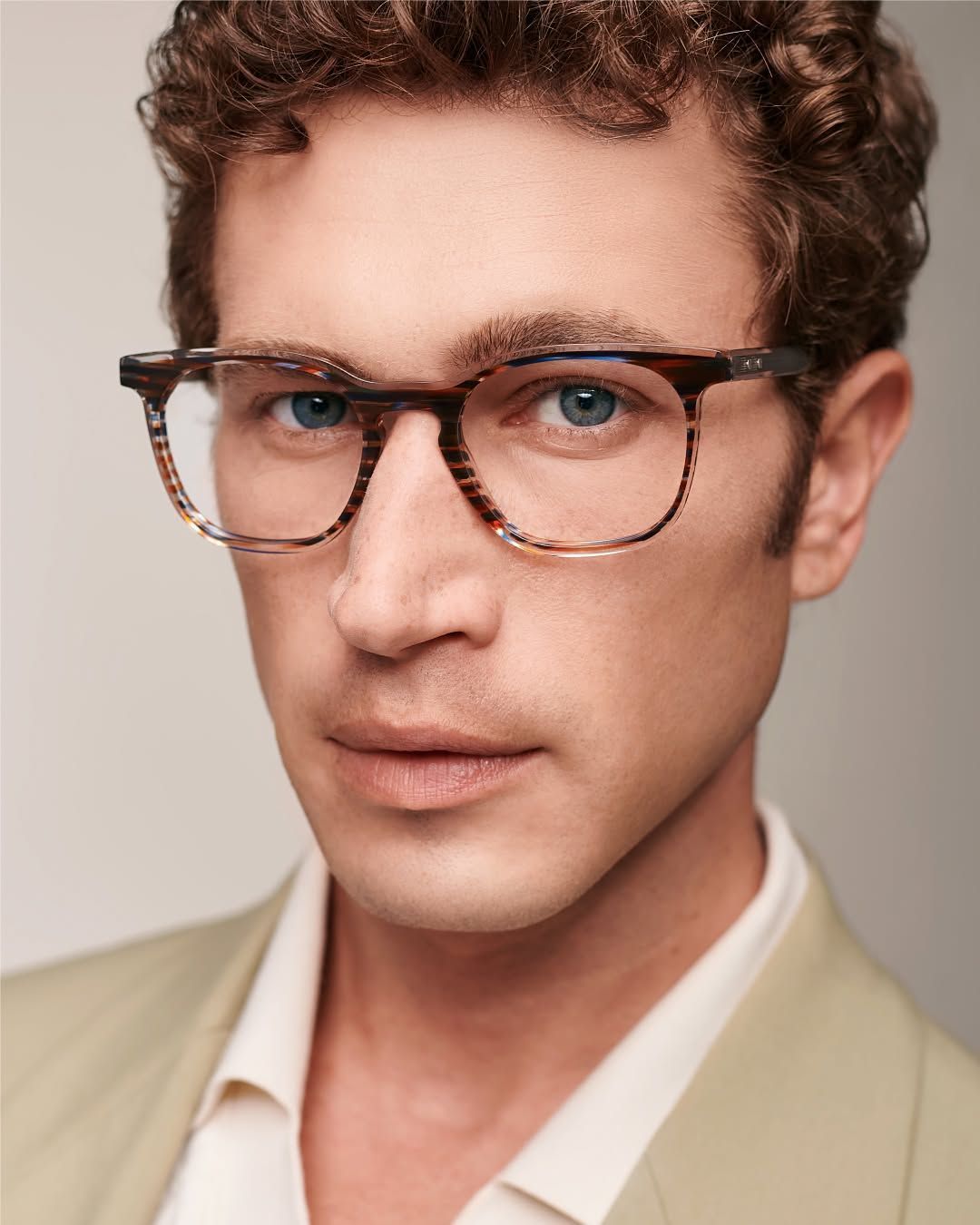 A man wearing glasses and a suit is looking at the camera