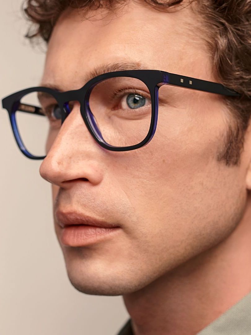 A man wearing glasses is looking at the camera.