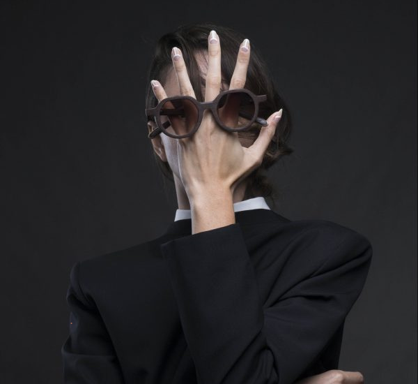A woman wearing sunglasses covering her face with her hands