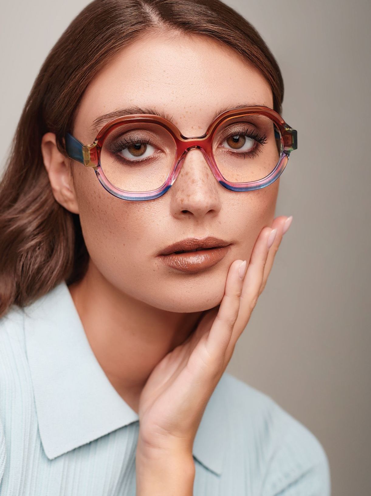 A woman wearing glasses holds her hand to her face