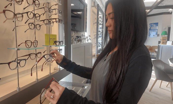 Woman looking at eyeglasses on display in an optical shop.