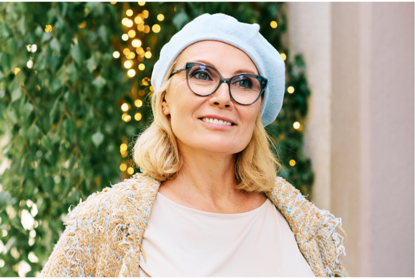 A woman wearing glasses and a beret is smiling.