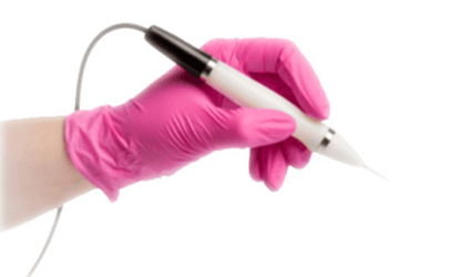 Hand in pink glove holds a white pen-like tool with a thin tip and a wire.
