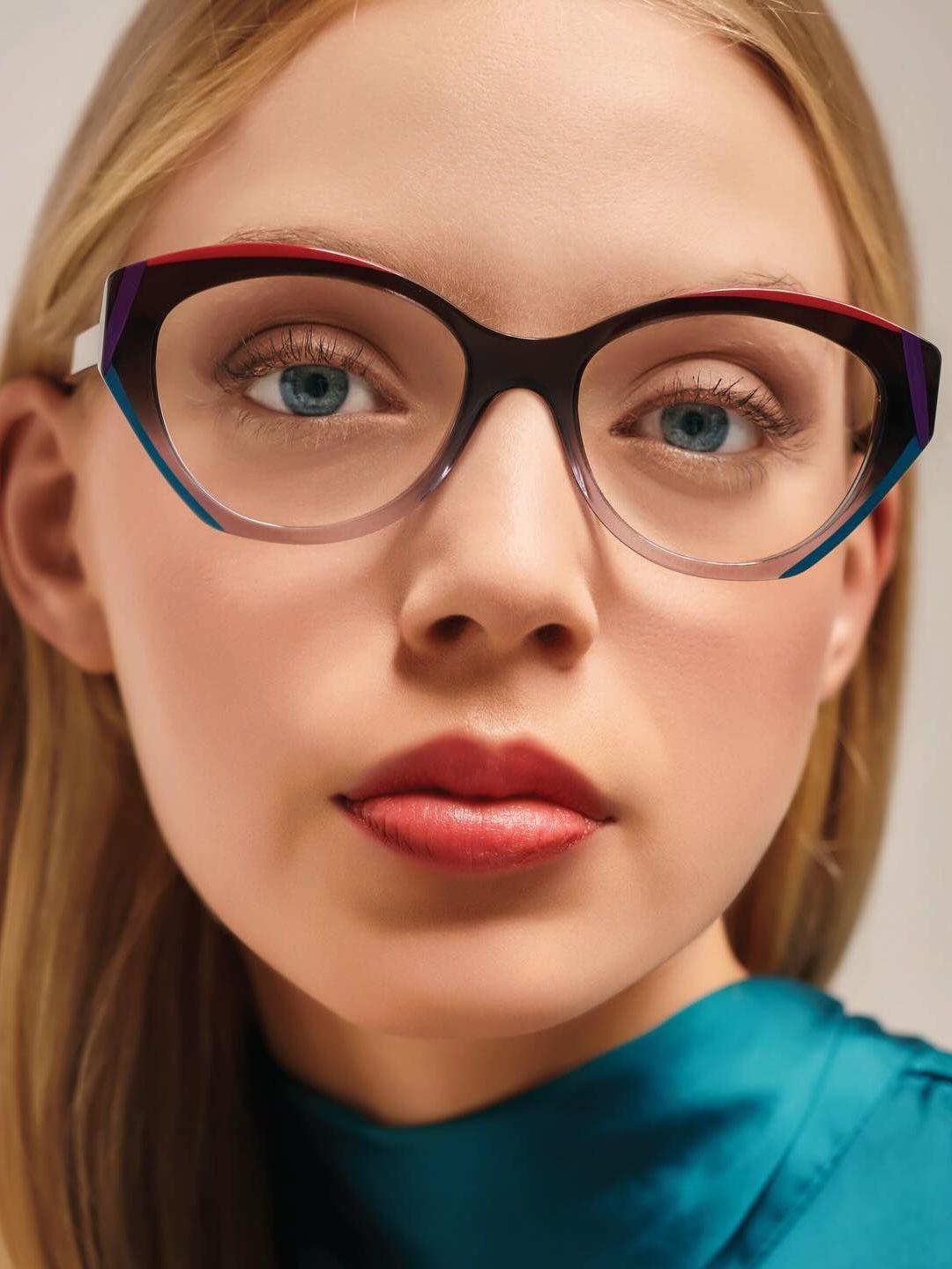 A close up of a woman wearing glasses and a blue shirt