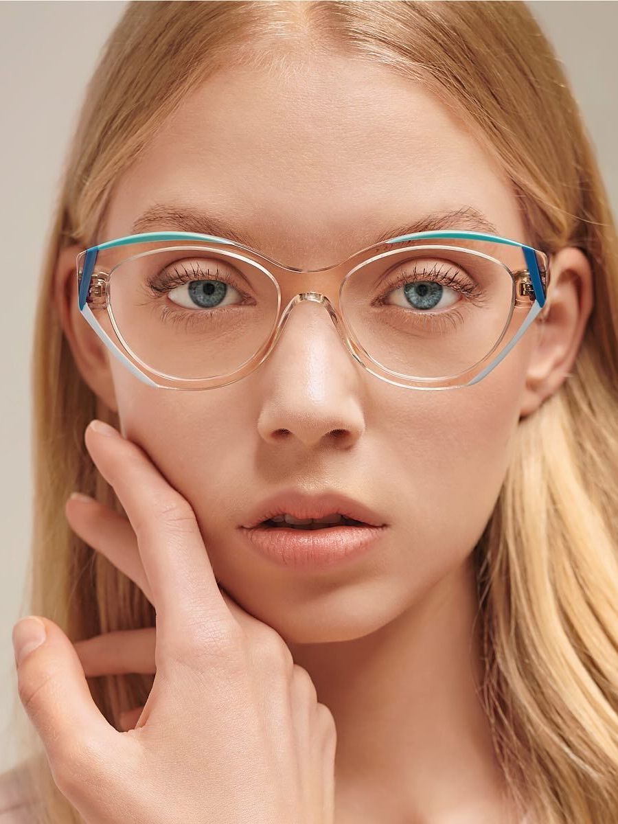 A woman wearing glasses is touching her face with her hand.