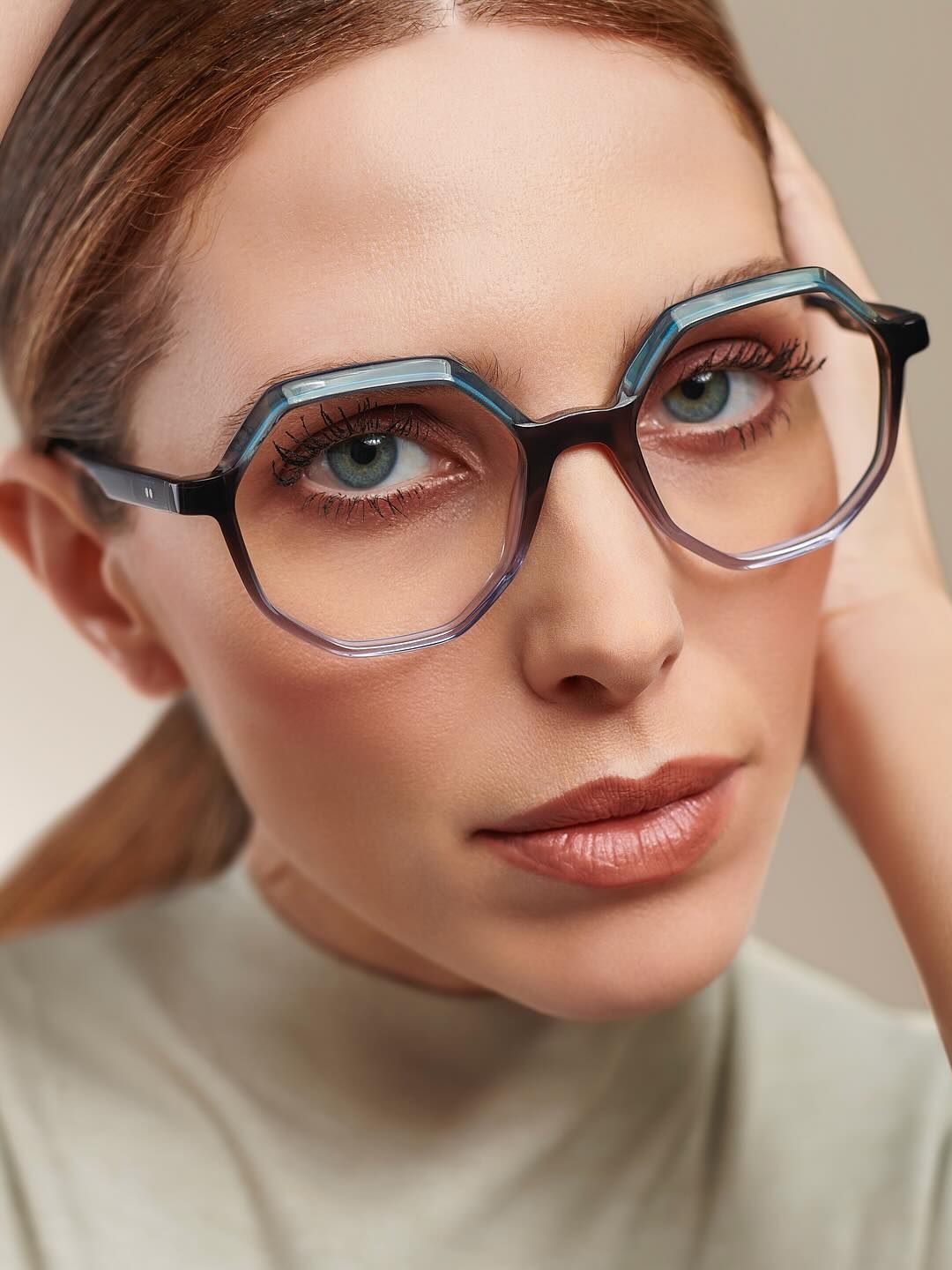 A close up of a woman wearing glasses and a green shirt