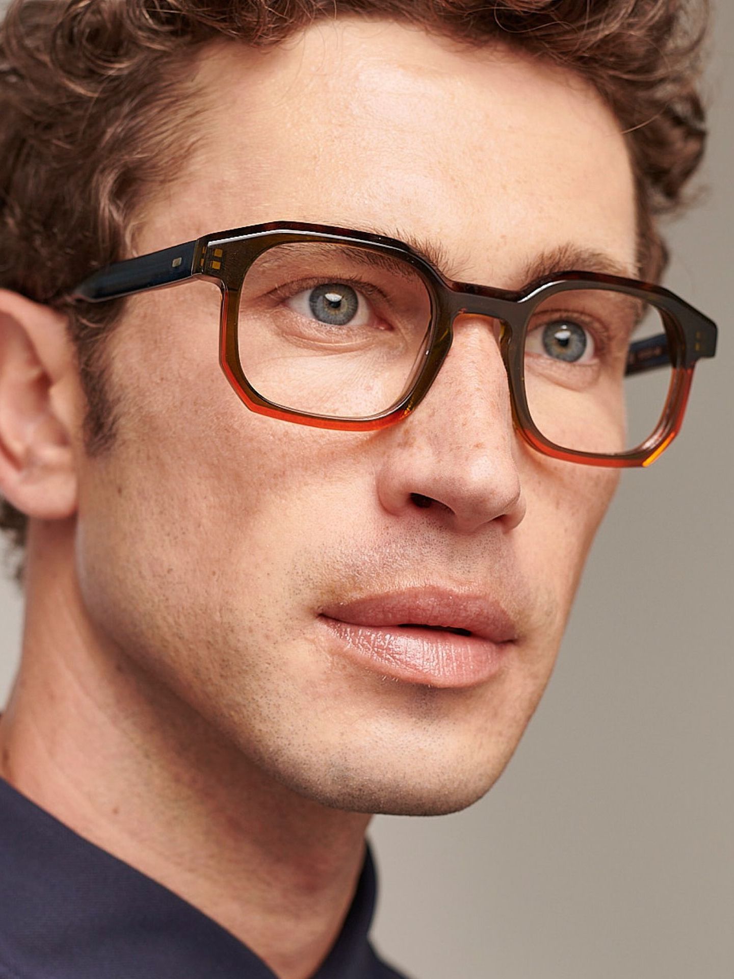 A close up of a man wearing glasses and a blue shirt.