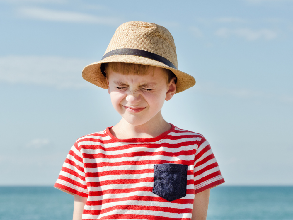 A young boy is squinting due to light sensitivity.