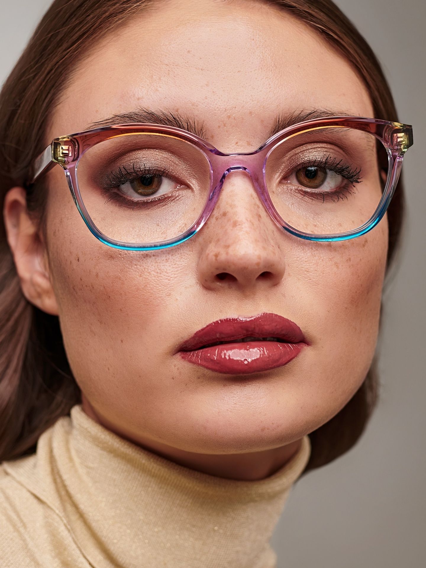 A close up of a woman wearing glasses and a turtleneck.