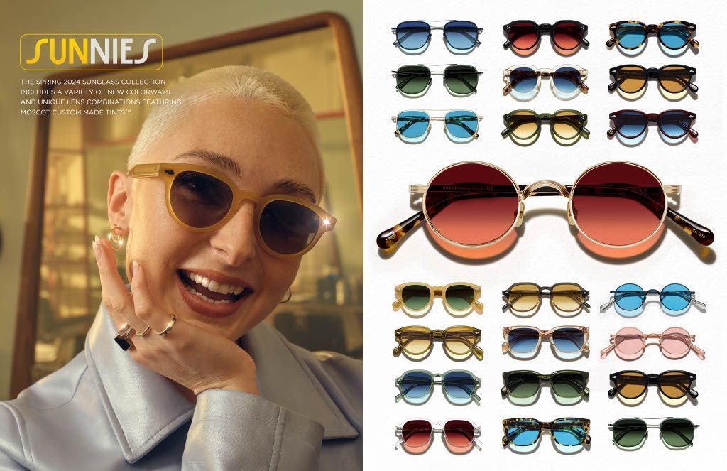 A woman wearing sunglasses is smiling next to a row of sunglasses.